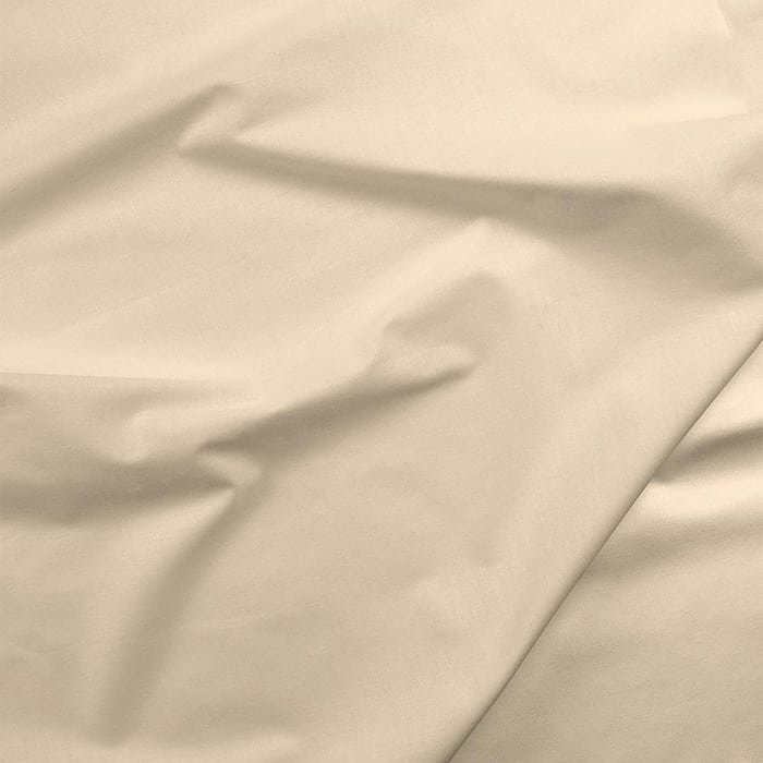 A close-up of Paintbrush Studio (PBS) Cotton Sateen Natural 118" Wide Quilt Backing Fabric shows crumpled beige folds and smooth shadows—perfect for quilt backing projects.
