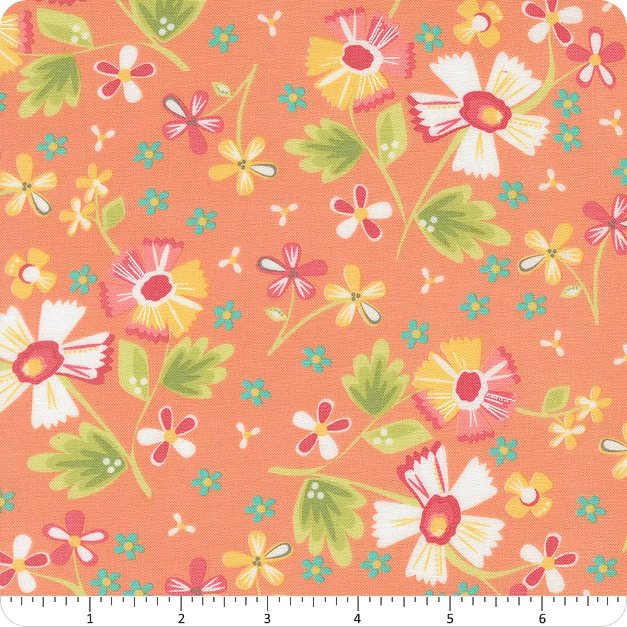 The In the Garden Coral Garden Flowers Fabric Yardage by United Notions features large white daisies, pink and yellow flowers, and green leaves on a peach background. A ruler at the bottom shows inch measurements for scale.