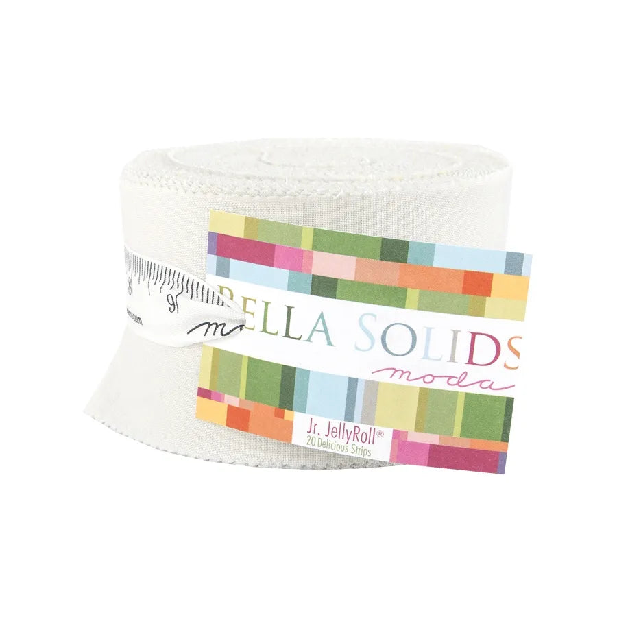 The Bella Solids Feather Junior Jelly Roll by United Notions features white fabric strips rolled and wrapped with a colorful label, tied with a ribbon printed to look like measuring tape.