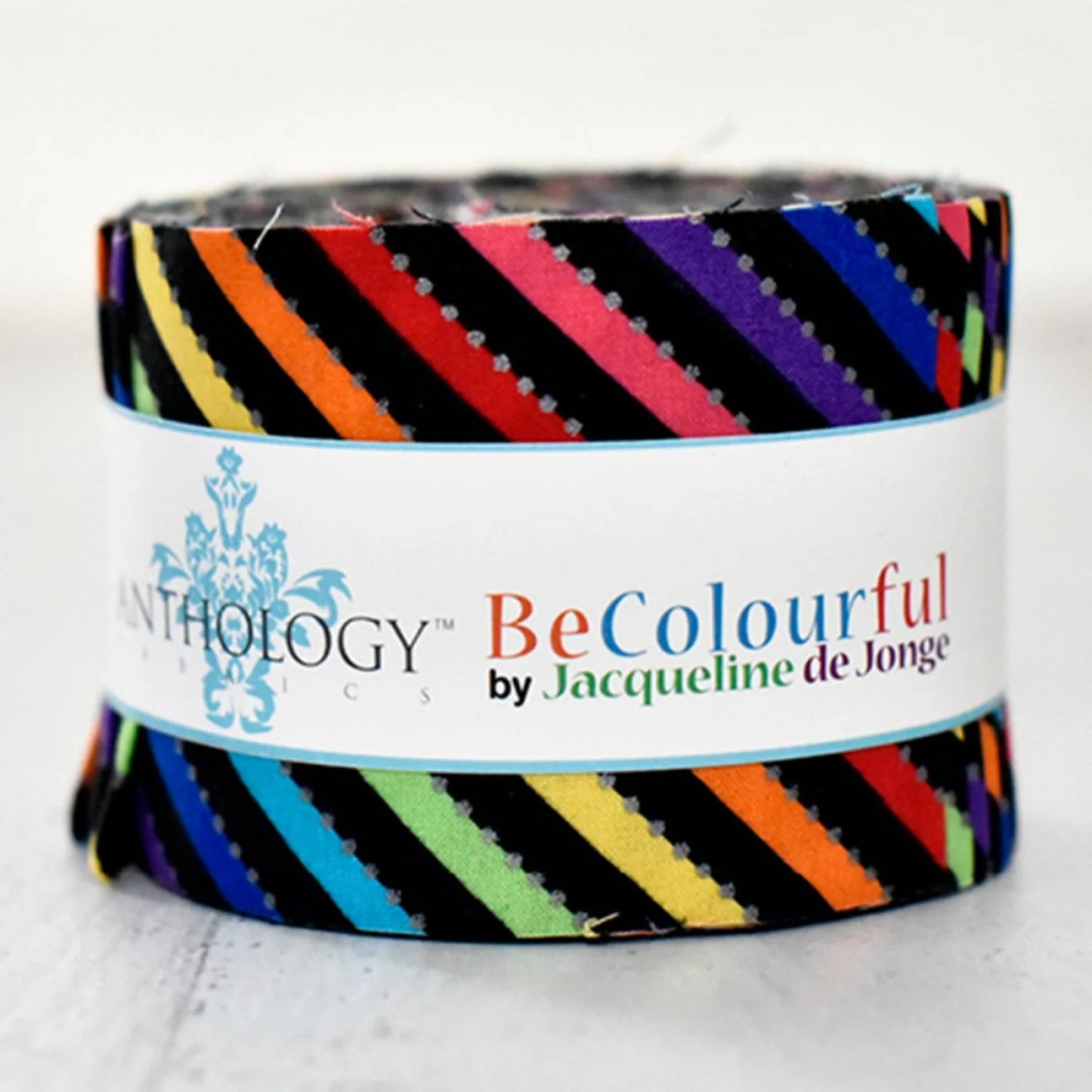 The Be Colourful Licorice Multi (Bias) 2.5" Strips 26ct features vibrant diagonal rainbow stripes on precut cotton strips, wrapped in a BeColourful by Jacqueline de Jonge & Anthology label, with bright patterns on a black background.