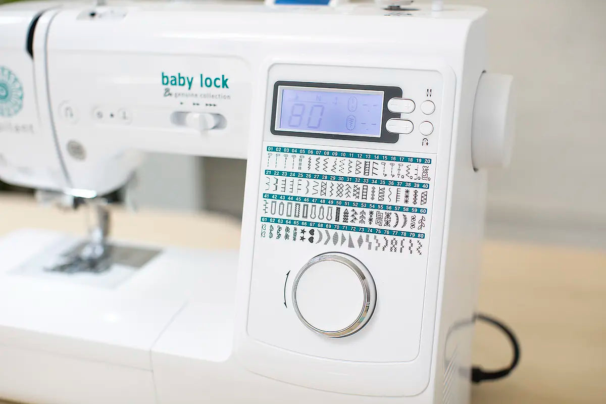Close-up of the Baby Lock Jubilant Sewing Machine—perfect for beginners—featuring multiple stitch patterns, an 80-pattern digital display, easy-access buttons, and a large silver dial on a light surface.