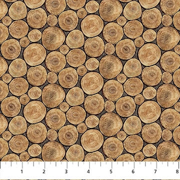 Lakeside Retreat Brown Logs Fabric by Northcott features closely spaced tree log cross-sections in various sizes with visible wood grain and rings. A white inch ruler runs along the bottom edge—ideal for quilting or crafts.