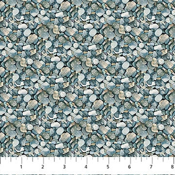 The Lakeside Retreat Green River Rocks Fabric Yardage by Northcott displays a repeating pattern of small, overlapping gray and beige stones (each about 1 inch wide), making it ideal for landscape quilts. Ruler in image shows inches for scale.