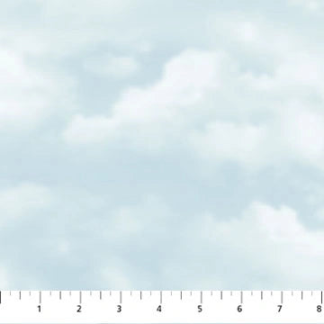 Lakeside Retreat Blue Clouds Fabric Yardage by Northcott features a light blue and white cloudy sky pattern on cotton, with a ruler along the bottom edge displaying measurements from 1 to 8 inches.