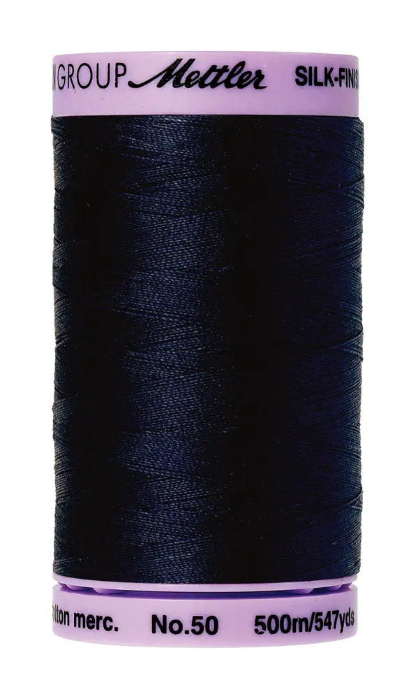 A spool of Mettler Cotton Silk Finish 50wt thread in Dark Blue, with 500 meters (547 yards), is ideal for quilting or as a cotton sewing thread.