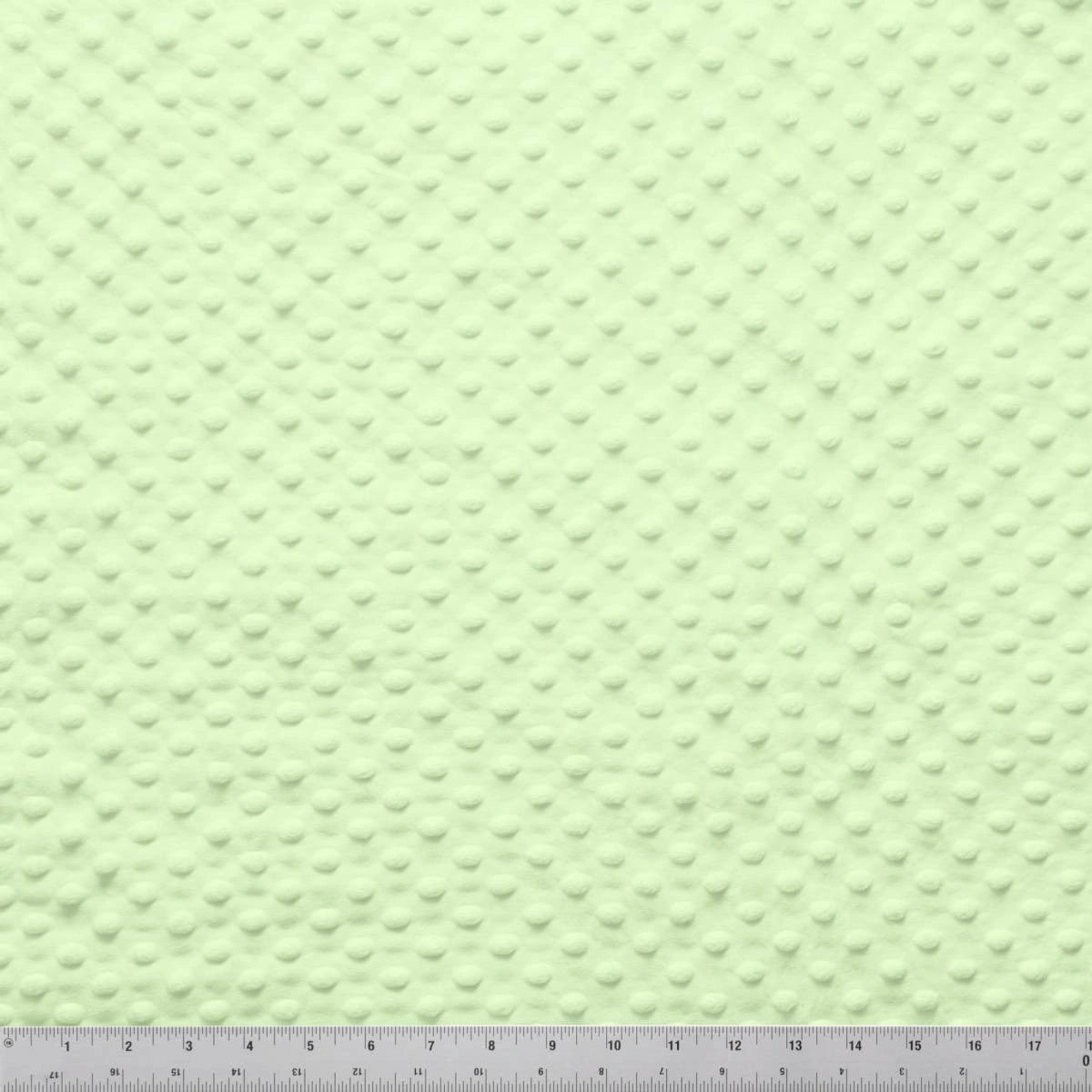 A close-up of Jaftex - Henry Glass Fabrics’ Minky Dots Sage 60" Wide Quilt Backing Fabric shows evenly spaced raised dots with a ruler for scale—ideal for quilting projects.
