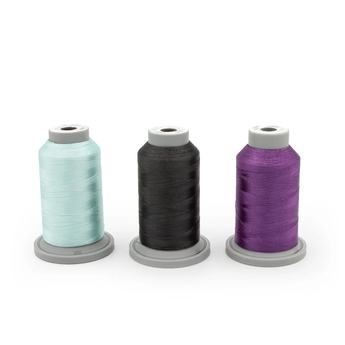 The Eclipse Kaleidoscope Aurora Glide Thread Bundle features three spools of polyester thread in light blue, black, and purple—ideal for machine quilting projects.