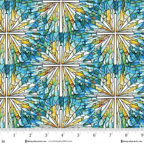 Faith in Full Color Stained Glass Cross Fabric Yardage by Jaftex - Henry Glass Fabrics features a blue, green, and yellow cross pattern with starburst shapes. A ruler in inches runs along the bottom for scale; ideal for faith or quilting projects.