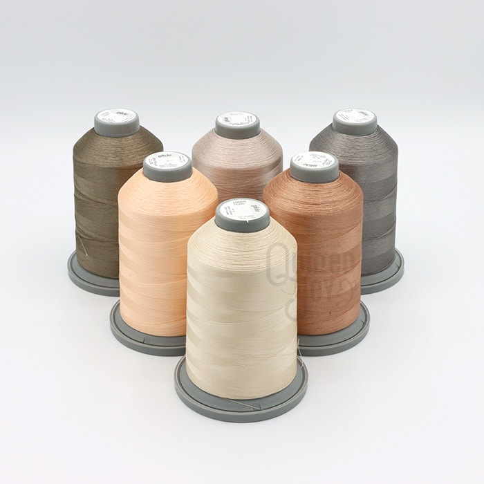 Six spools of Hab+Dash Glide Thread New Neutrals Bundle—beige, tan, brown, and gray shades—arranged in a circle on white. Exclusive to Quilted Joy, these polyester threads are perfect for quilting projects.