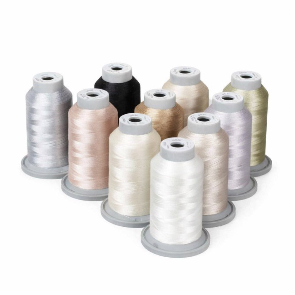 Nine spools from the Hab+Dash Glide Thread Everyday Neutrals Bundle—white, beige, grey, black, and light gold—stand upright in three rows on a white background. Perfect polyester quilting thread for versatile projects.