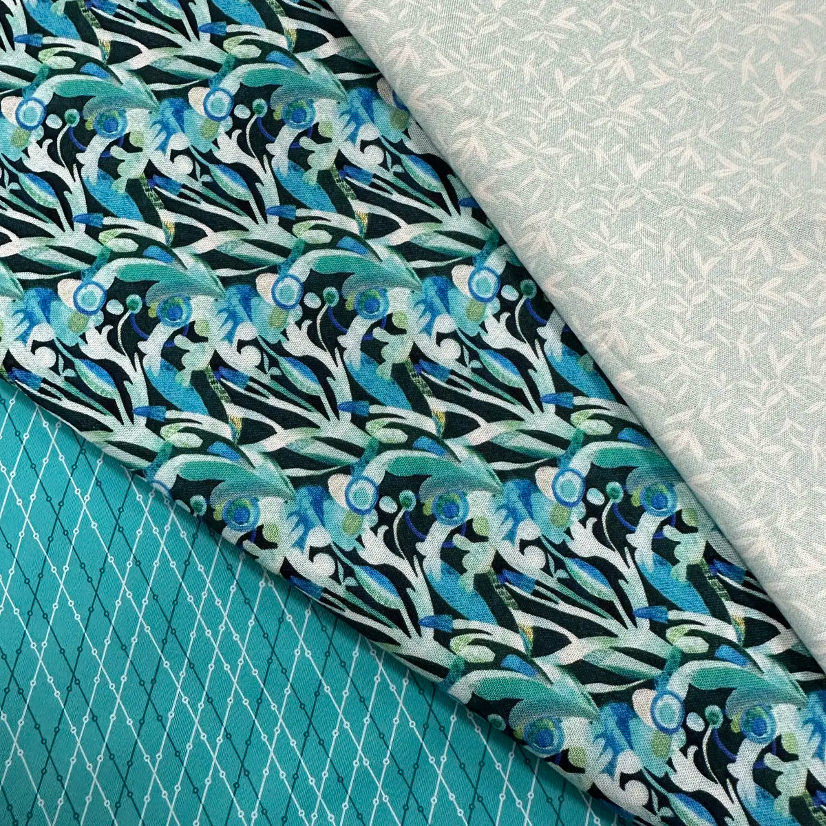 The Quilted Joy L'Heure Bleue Teal 3 Yard Quilt Top Bundle features three 100% cotton fabrics—blue-green abstract floral, pale geometric leaf, and teal diamond grid—ideal for Fabric Cafe 3-yard quilt books.