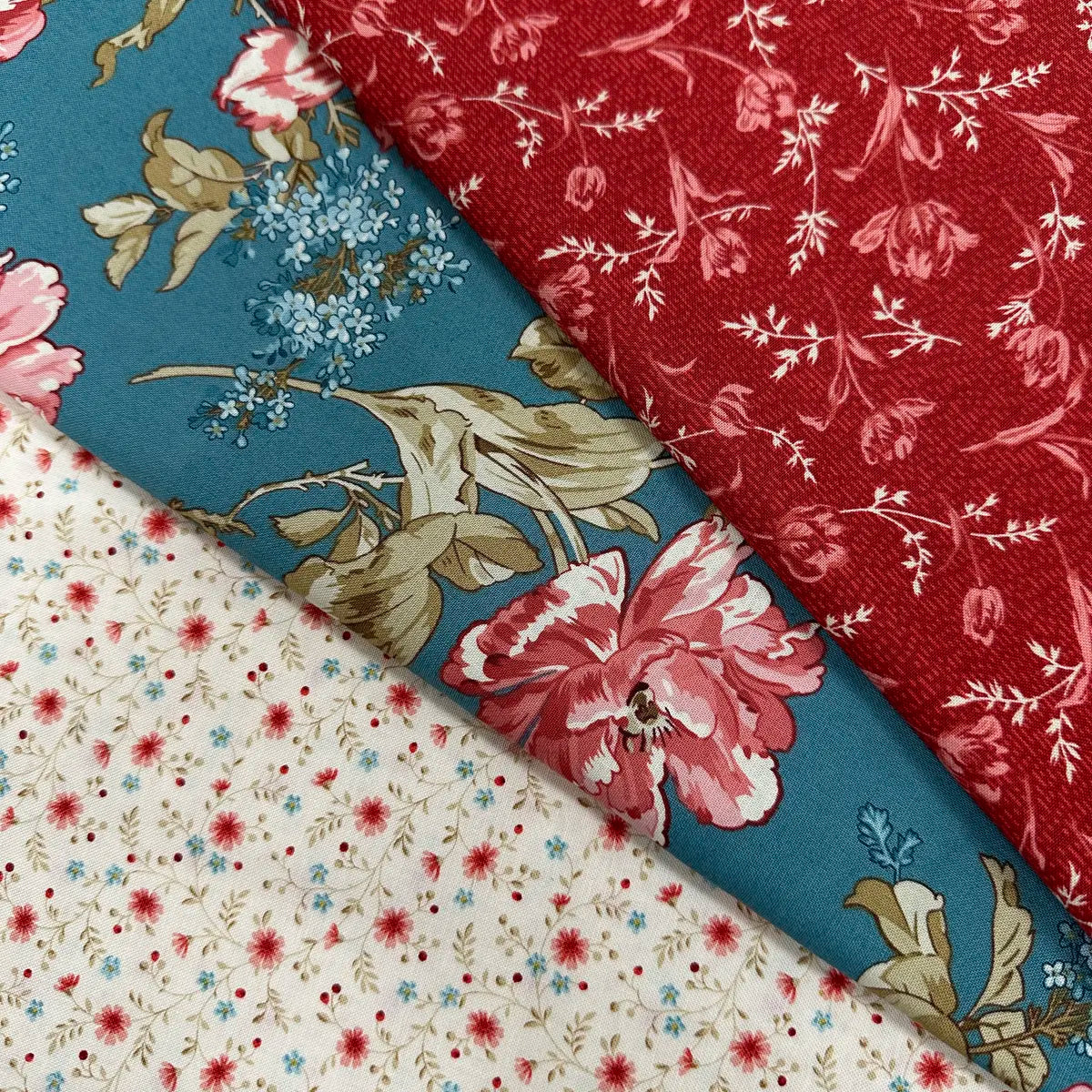 The Quilted Joy Lighthouse Summer Breeze 3 Yard Quilt Top Bundle includes three cotton fabrics: red with small white flowers, teal with large pink and beige blooms, and cream with tiny red and blue flowers, all in floral patterns.