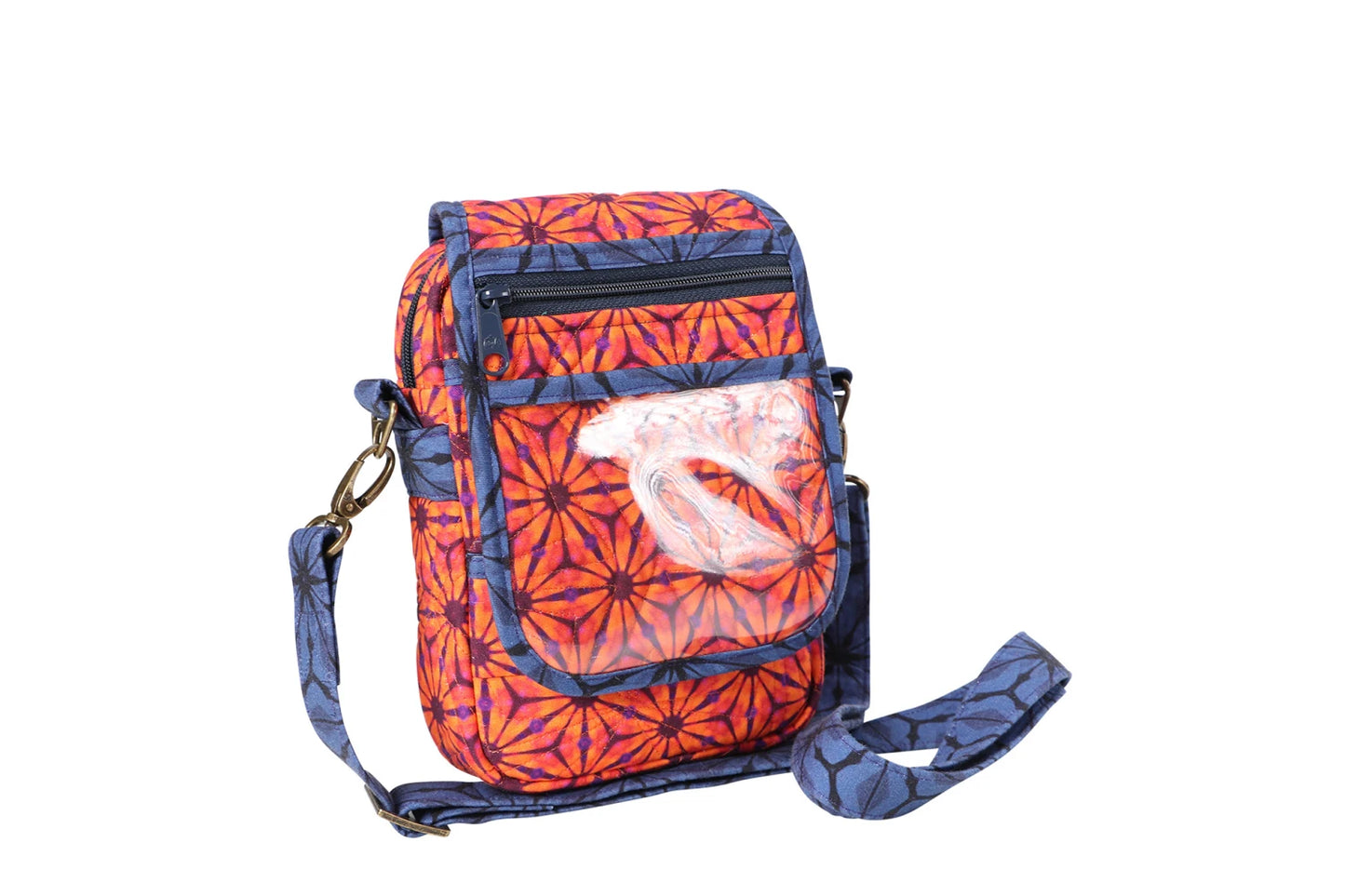 The On the Go 2.0 Quilt Pattern features a small crossbody bag with an orange and purple geometric pattern, blue adjustable strap, front zip pocket, and a white embroidered design on the flap.