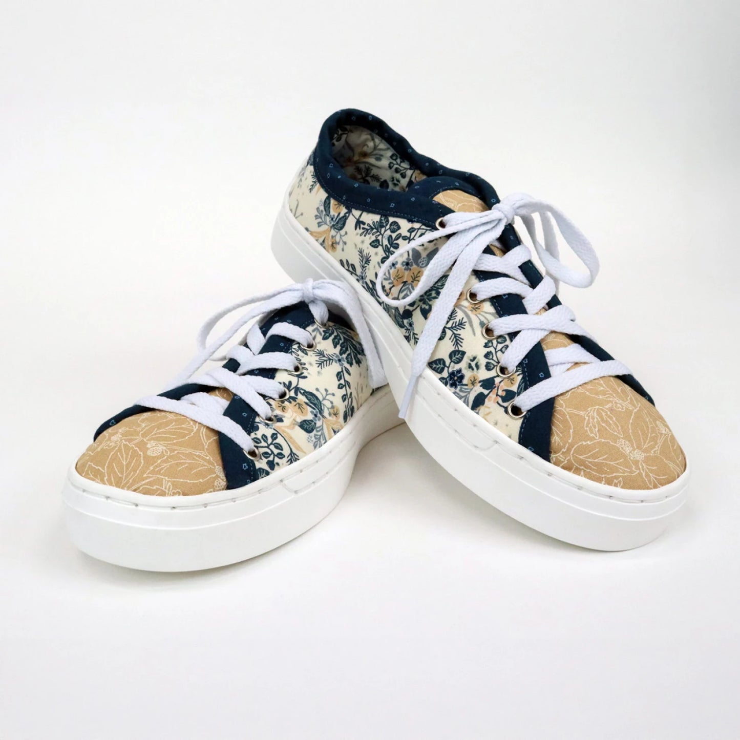 The Patchwork Kicks White Shoe Kit by Checker Distributor features custom sneakers with white soles and laces, tan toe caps, and a blue and cream floral pattern on the uppers, shown against a plain white background.