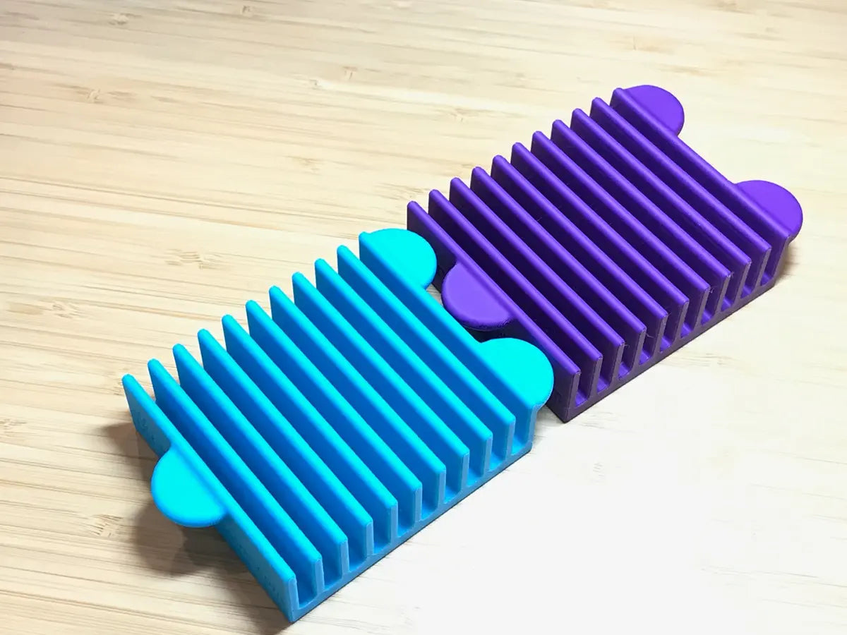 A blue silicone Ruler Stand 10 Slot 3in keeps your quilting rulers organized, featuring evenly spaced ridges—perfect for neat storage and easy access on your crafting table.