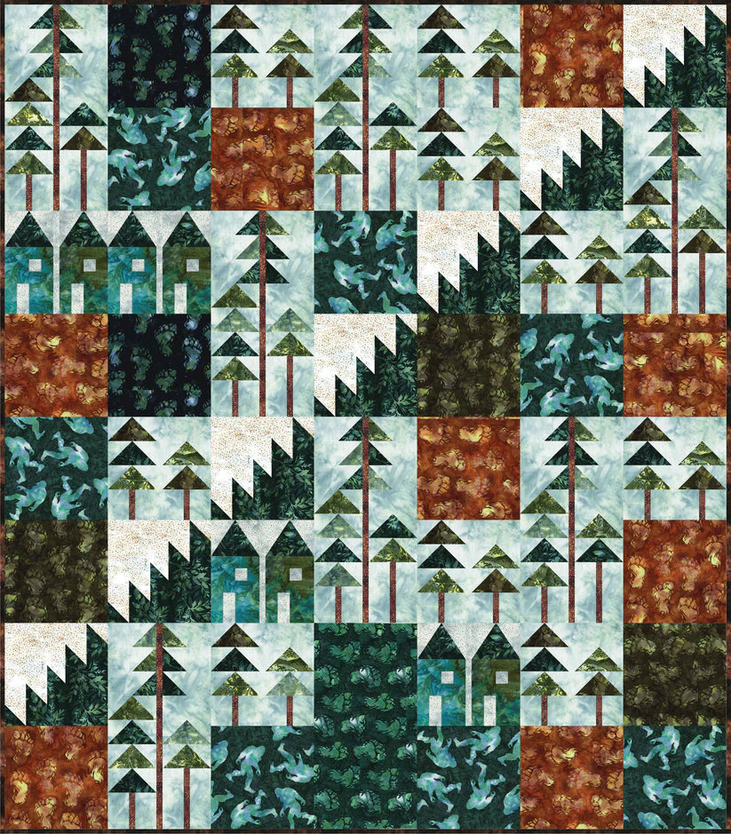 The "Where's Squatch? Quilt Kit" by Quilted Joy features a patchwork design of houses, trees, and mountains in earth tones, greens, blues, and browns for a nature-inspired, forest village look.