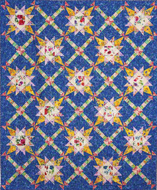 Inspired by the Love of Quilting Lavender Roads Quilt Kit - PRESALE from Quilted Joy, this colorful patchwork quilt features a repeating star pattern in yellow, white, and patterned fabrics on a blue background.