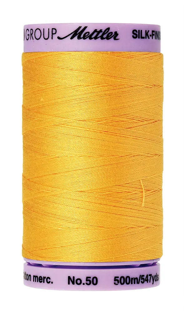 A spool of Mettler Cotton Silk Finish 50wt 500m Summersun thread, bright yellow with a purple plastic cap and base.