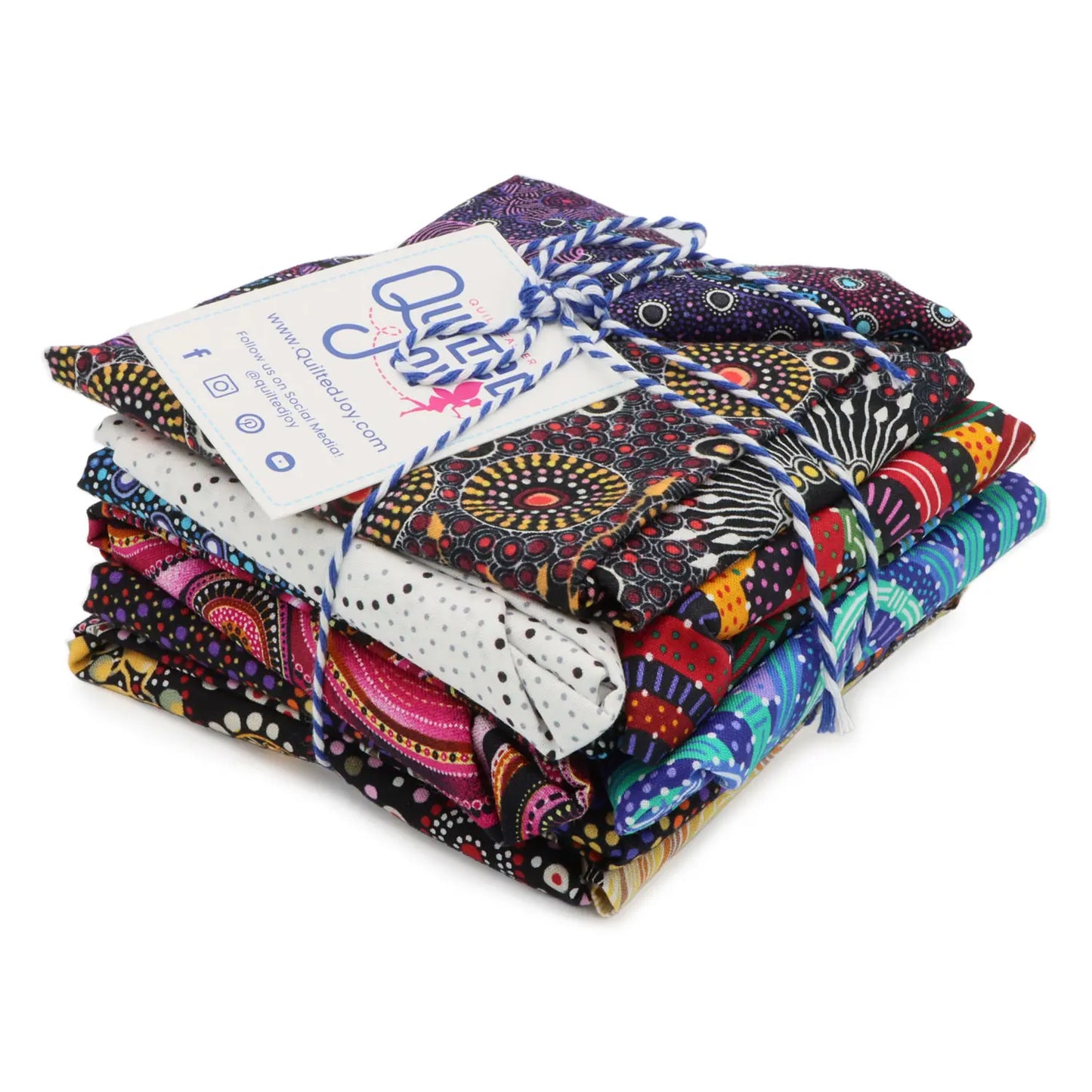 The Aboriginal Bush Fat Quarter Bundle 12 Count by M & S Textiles Australia features 12 vibrant, patterned fabric squares tied with string and a business card, showcasing bold Aboriginal-inspired designs in assorted colors.