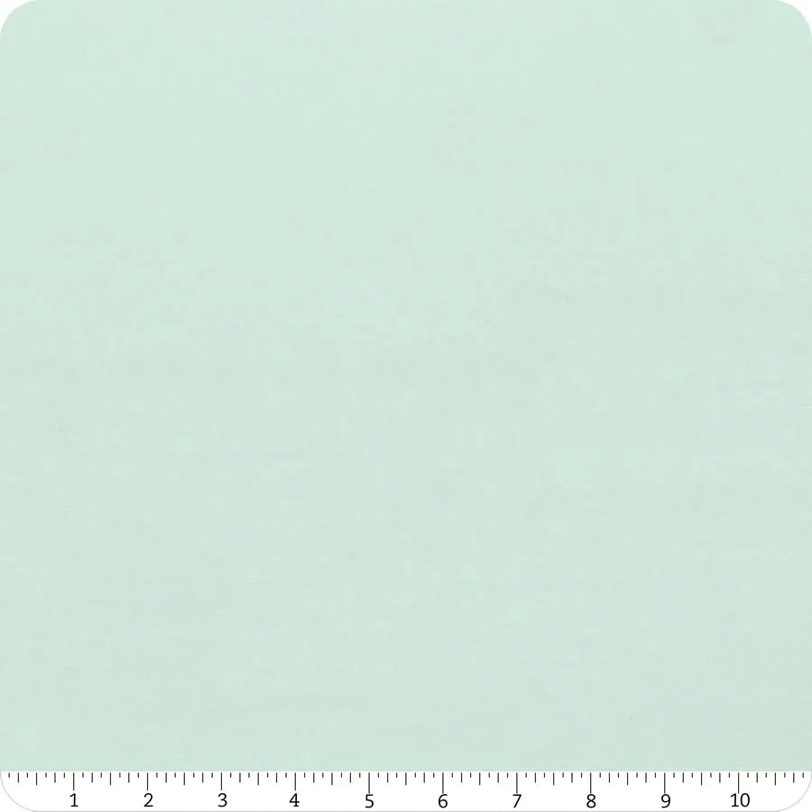A 10" Bella Solids Home Town Sky Junior Layer Cake square by United Notions in light mint green with subtle texture, shown with a white inch ruler for scale. The fabric swatch has rounded corners.