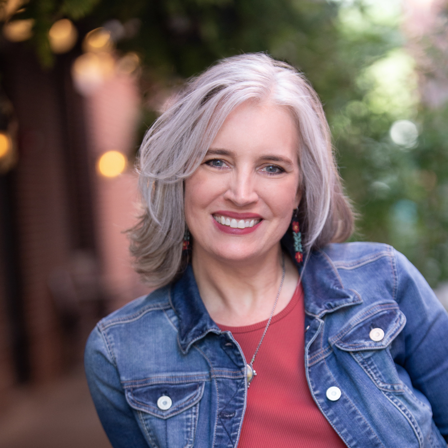 Bethanne Nemesh, with shoulder-length gray hair and a denim jacket over a red top, stands outdoors after hosting the "Bethanne Nemesh Yarn Couching Trunk Show" on Friday, March 13th, 2026.