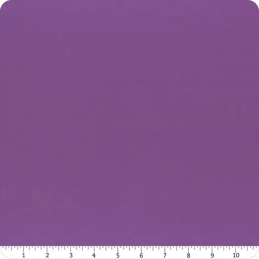 A square piece of Riley Blake Confetti Cotton™ Iris Fabric Yardage is shown with a white ruler (1 to 10 inches) along the bottom edge, indicating size. The purple fabric has rounded corners.