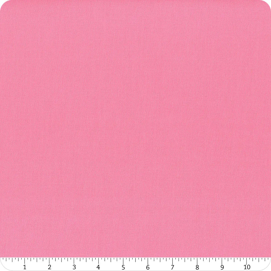 A square of Riley Blake Confetti Cotton™ Piglet Pink Fabric Yardage is displayed on a white background with a ruler along the bottom edge, marked from 1 to 10 inches, showing the fabric’s subtle texture.