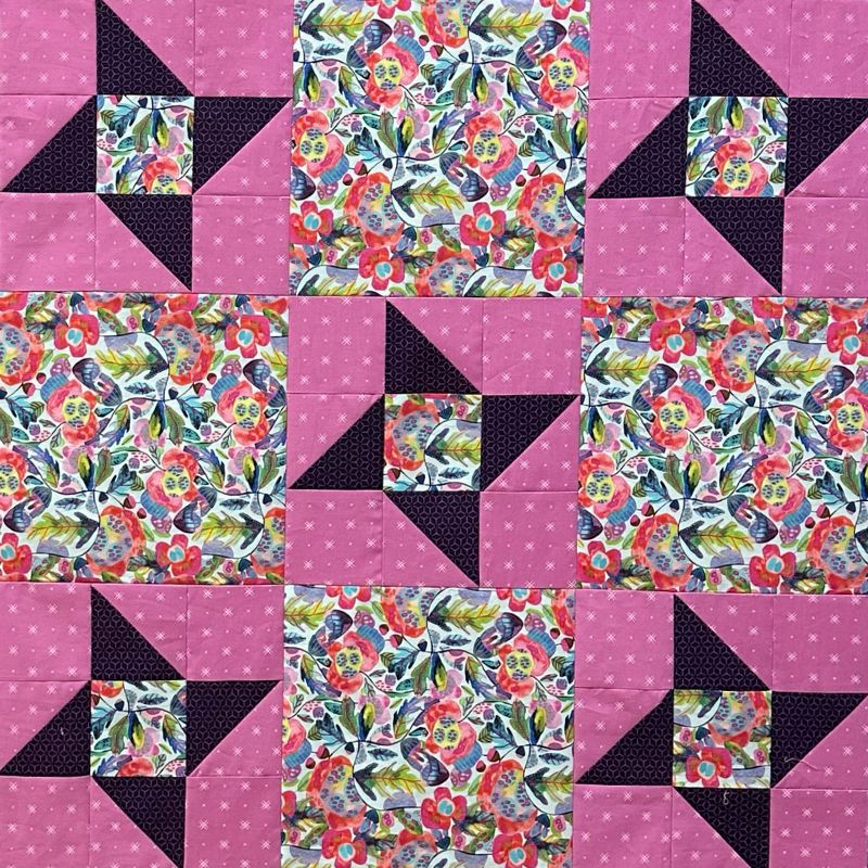 My Next Quilt Class features a repeating pattern of floral squares and star shapes, crafted with half-square triangles using pink and dark purple fabrics, plus colorful floral prints with leaves and flowers.