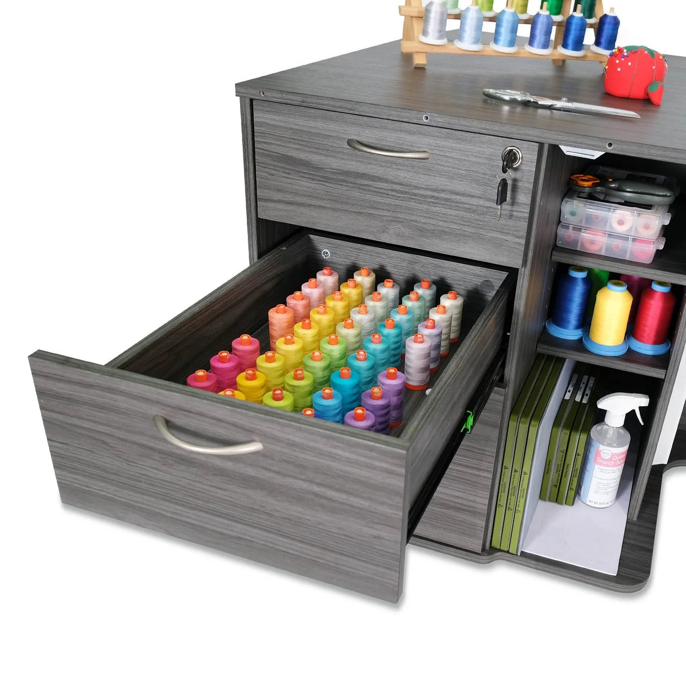 The Kangaroo Sydney Sewing Cabinet with Electric Lift by Arrow Companies, LLC features an open drawer filled with colorful thread spools and extra sewing supplies arranged on its shelves and tabletop.