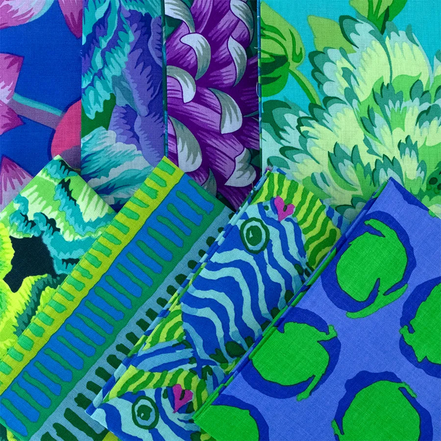 Colorful patterned fabrics with bold floral, fish, and leaf designs in blue, green, purple, and pink hues are arranged in overlapping, vertical and diagonal strips.