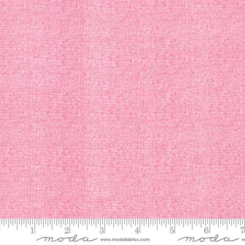 The Thatched Primrose 108" Wide 3 Yard Quilt Fabric Back Pack features textured pink Moda fabric with a subtle grid design. A white inch-marked Moda ruler lines the bottom edge, making it perfect for quilt backing.