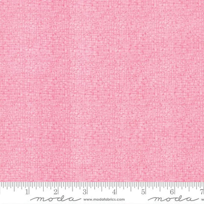 The Thatched Primrose 108" Wide 3 Yard Quilt Fabric Back Pack features textured pink Moda fabric with a subtle grid design. A white inch-marked Moda ruler lines the bottom edge, making it perfect for quilt backing.