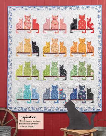 Scrap Quilting With Wendy Sheppard" by Checker Distributor features rows of colorful, patterned cats—ideal for scrap quilt fans. Displayed on a red wall, a black cat silhouette sits nearby with a sign about the creative process.