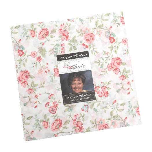 The United Notions Abide 10" Layer Cake features floral squares in pink, green, and white, with a label displaying a woman’s photo and the word "Abide.