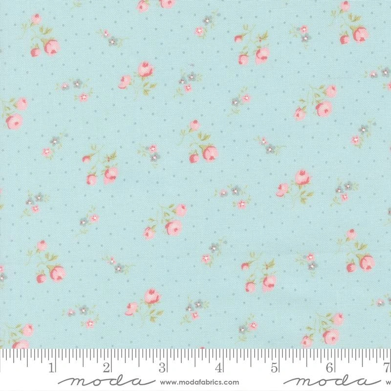Abide Light Blue Small Floral Fabric Yardage by United Notions features a subtle dotted pattern with small pink roses and green leaves. A ruler in the photo shows inches for scale, perfect for quilting and crafts.