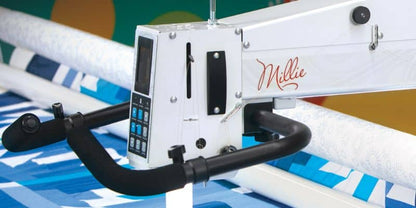 Close-up of an APQS DEMO Lenni 22" Long Arm Quilting Machine with Standard Bliss Table/Frame, featuring black handles and a digital control panel, shown over a blue and white quilt.
