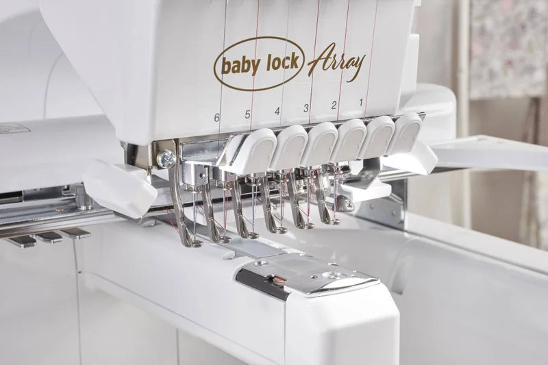 Close-up of the Baby Lock Array 6 Needle Embroidery Machine, displaying its six numbered needle positions with threads, metal needle bars, and part of the white machine body.
