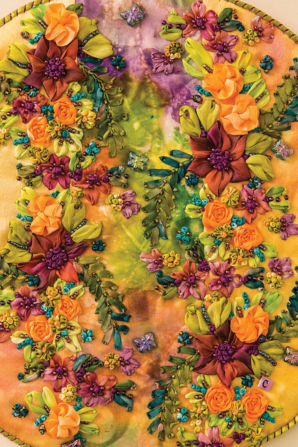 The Embroidery Stitching Handy Pocket Guide from Checker Distributor features inspiring symmetrical floral designs with vivid embroidered flowers, leaves, and bead accents—perfect for hand stitchers seeking intricate embroidery ideas.