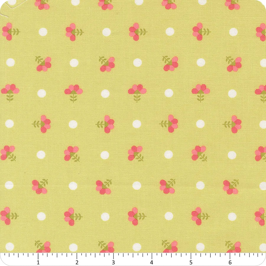 In the Garden Lime Dotted Sprig Florals Fabric Yardage by United Notions features yellow fabric with small white polka dots and pink flower trios on green stems in a grid. A ruler in inches is shown at the bottom for measurement.