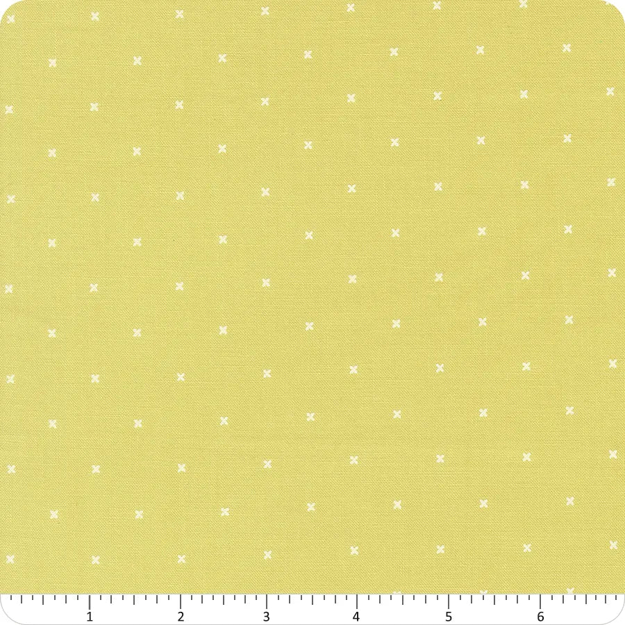 The In the Garden Lime Tiny Peel Fabric Yardage by United Notions features light yellow fabric with small white Xs and is shown with an inch-marked measuring guide from 1 to 6 along the bottom edge for easy yardage reference.