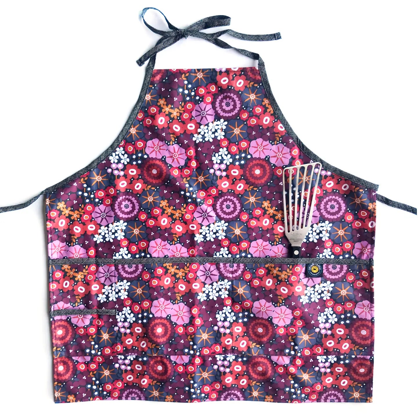 Floral patterned apron with a whisk holder on a white background