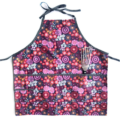 Floral patterned apron with a whisk holder on a white background