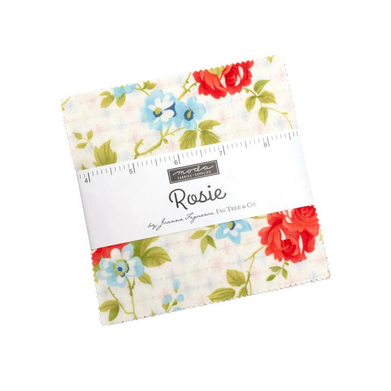 A Rosie 5" Charm Pack by United Notions, featuring floral quilting cotton in red, blue, and green on white, wrapped with a Moda Rosie by Joanna Figueroa Fig Tree & Co. label adorned with a ruler design.