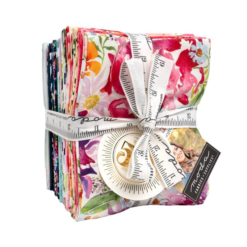 The Soulstice Fat Quarter Bundle by United Notions offers colorful, floral-print quilting fabric squares, neatly tied with a white ribbon printed like a measuring tape and attached tags.