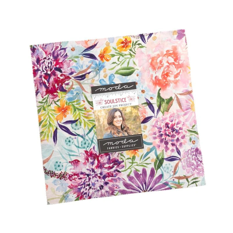 The Soulstice Layer Cake by United Notions features vibrant pink, purple, and yellow floral patterns on light blue 10-inch fabric squares—perfect for quilting projects.