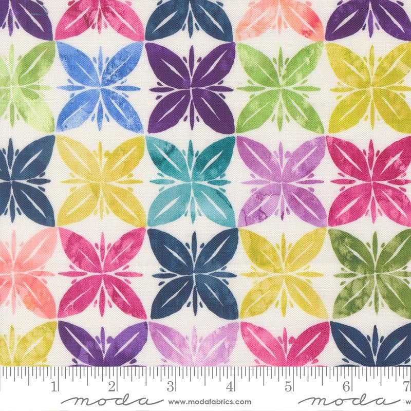 Soulstice Rainbow Fabric Yardage by United Notions features a colorful, repeating four-petal floral pattern in quilting hues, arranged in rows on white. A ruler is shown at the bottom for scale.