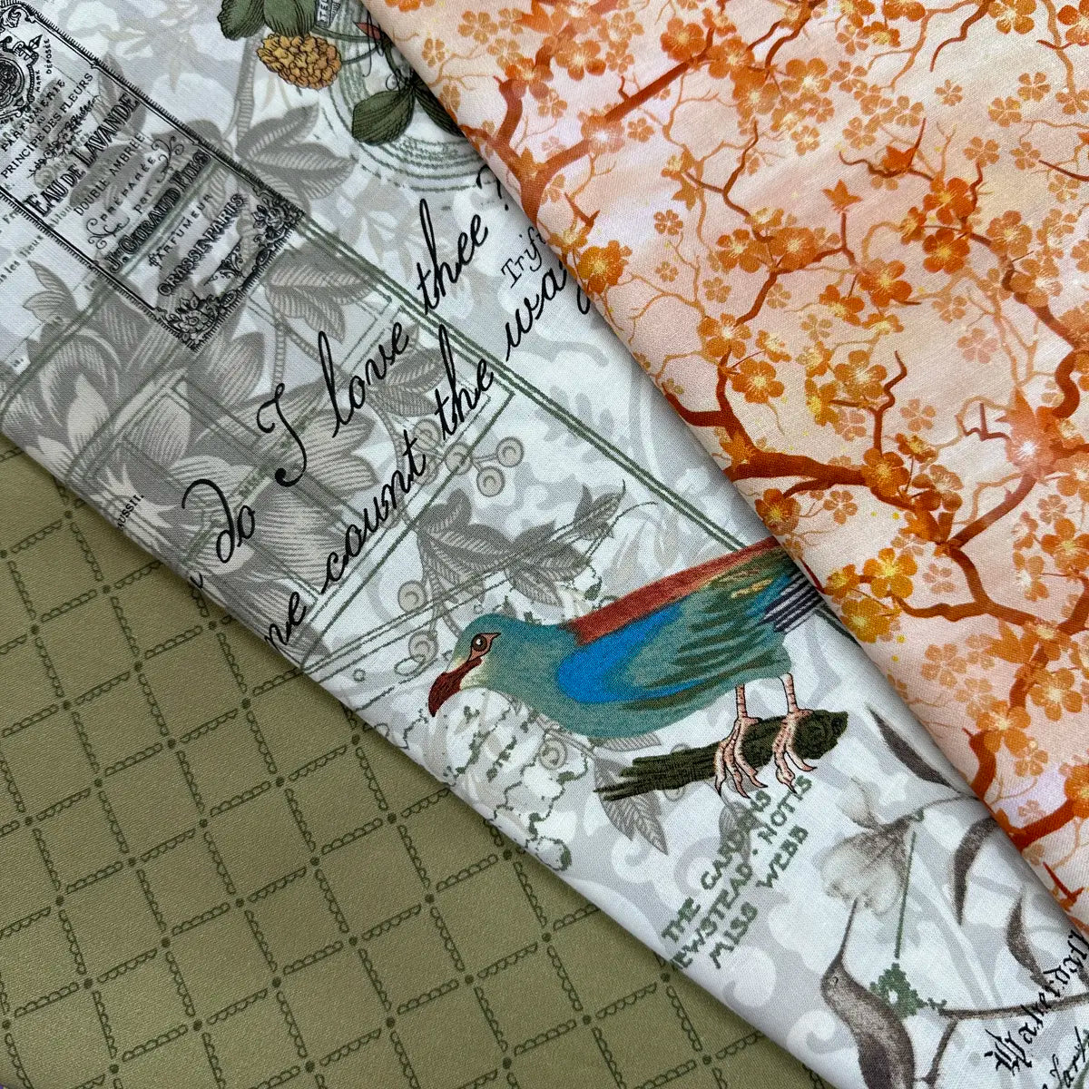 The Quilted Joy 3 Sisters Collage Bright 3 Yard Quilt Top Bundle features green grid, white vintage bird with text, and orange cherry blossom fabrics—ideal for creative quilt projects or adding flair to your fabric stash.