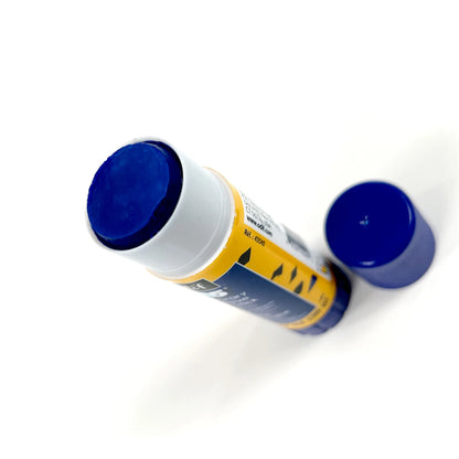 A 505 Temporary Adhesive Stick by Checker Distributor, with the blue cap removed, rests on a white surface. The visible glue at the top is water-soluble and ideal for fabric applique; the cap lies beside it.