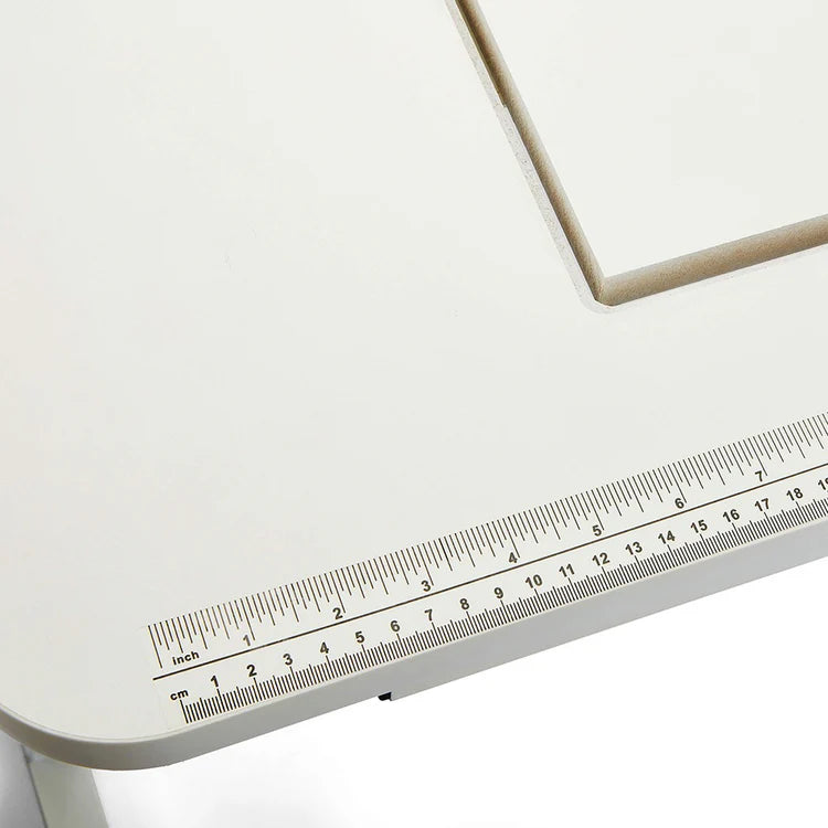 The Arrow Gidget II Sewing Table by Arrow Companies, LLC features a cream-colored tabletop with a built-in ruler showing inch and centimeter marks, plus a visible recessed groove near the top right corner.