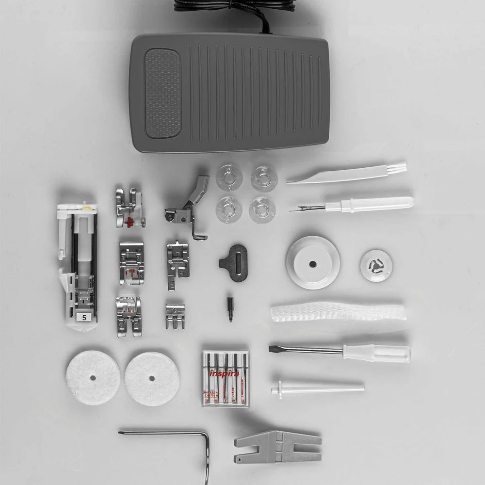 Quilted Joy's Pfaff Quilt Ambition 635 Sewing and Quilting Machine accessories—presser feet, bobbins, needles, spool caps, and more—are displayed neatly on a white surface.